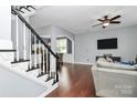Spacious living room featuring hardwood floors, a ceiling fan, stairs and open views to the kitchen at 7544 Rolling Meadows Ln, Huntersville, NC 28078