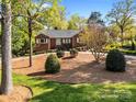 Beautifully landscaped front yard of a brick home with mature trees and a circular driveway at 961 Confederate Ave, Salisbury, NC 28144
