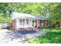 Attractive home features a brick facade, walkway with stone edging, and an American flag on display at 1115 Grovewood Dr, Charlotte, NC 28208