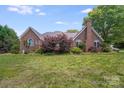 Brick home exterior with a spacious backyard featuring mature trees and lush greenery at 1337 Braeburn Nw Rd, Concord, NC 28027