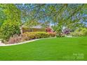 Charming brick home with a lush green front yard and mature trees, perfect for outdoor enjoyment at 1337 Braeburn Nw Rd, Concord, NC 28027