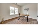 Bright office featuring hardwood floors, a large window, and a modern desk setup at 18011 Wilbanks Dr, Charlotte, NC 28278