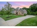 Scenic home with a lush green lawn, mature trees, and a long driveway leading to the stone and shingle facade at 320 Eden Hollow Ln, Weddington, NC 28104