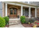 Inviting front porch with stone steps, a decorative double-door entry, and comfortable seating area at 320 Eden Hollow Ln, Weddington, NC 28104