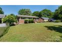 Traditional brick home with lush lawn, mature trees, and an American flag at 3400 Barfield Dr, Charlotte, NC 28217