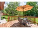 Outdoor deck featuring an umbrella table set, wooden railings, and a view of the green backyard space at 3932 Slagle Dr, Charlotte, NC 28215