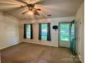 Bright living room with a ceiling fan, neutral carpeting, and an exterior door at 401 Overlook Dr, Monroe, NC 28110