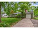 Cozy home with attached garage, green siding, mature trees, and well-maintained lawn at 408 Idlewood Dr, Kannapolis, NC 28083