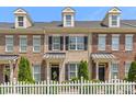 Brick townhome showcasing dormers, black shutters, landscaping, and a white picket fence at 4313 Courtly Ln, Belmont, NC 28012