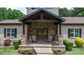 Inviting covered front porch with stone pillars, wooden accents, seating, and charming decor details at 4616 Gold Finch Dr, Denver, NC 28037