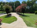 Beautifully landscaped front yard featuring a curved concrete walkway and vibrant flowering trees at 4616 Gold Finch Dr, Denver, NC 28037