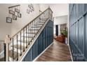 Open entryway with hardwood floors, staircase and black iron railings, with a glimpse of the living room at 5014 Forest Hills Pl, Fort Mill, SC 29707
