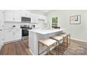 Modern white kitchen with an island, stainless steel appliances, and barstool seating at 5540 Pamplona Way, Charlotte, NC 28214