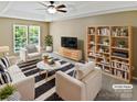 Bright living room with modern furniture, striped rug, and open shelving with plants and books at 903 Furman Ct, Fort Mill, SC 29708