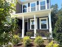Inviting front porch adorned with stone accents and elegant white columns at 9945 Cask Way, Huntersville, NC 28078