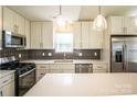A bright kitchen with stainless steel appliances, white cabinetry, stylish backsplash, and large center island at 1004 Johnson St, Charlotte, NC 28206