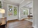 Open foyer with white french doors leading into a home office featuring a large window and custom built-in shelving at 1014 Harrogate Ln, Matthews, NC 28104