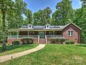 Brick home with a welcoming front porch, manicured lawn, and a walkway leading to the charming front door at 10545 Mount Holly Huntersville Rd, Huntersville, NC 28078