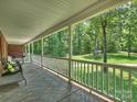 Covered porch with tiled flooring offering a scenic view of the lush, tree-filled backyard at 10545 Mount Holly Huntersville Rd, Huntersville, NC 28078