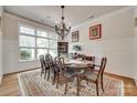 Bright dining room boasts large windows and detailed chandelier with an elegant table set on a decorative rug at 18311 Rosapenny Rd, Charlotte, NC 28278