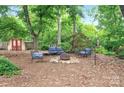 Secluded backyard oasis featuring a cozy fire pit with seating and mature trees for ultimate relaxation at 3430 Rea Rd, Charlotte, NC 28226