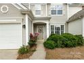 Inviting front entryway featuring a decorative wreath, blooming roses, and lush green bushes at 8040 Flanders St, Charlotte, NC 28277