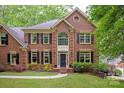 Beautiful two-story brick home with lush landscaping and a welcoming entrance in a wooded setting at 8227 Lansford Rd, Charlotte, NC 28277