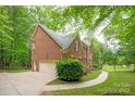 Brick home with attached garage, lush landscaping, and a winding walkway at 8227 Lansford Rd, Charlotte, NC 28277