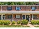 Traditional brick townhouse with black shutters and a cozy front porch with white railing and black front doors at 1215 Green Oaks Ln # H, Charlotte, NC 28205