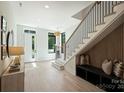 Bright entryway features a staircase with black railings, bench seating, and light wood floors at 1711 Summey Ave, Charlotte, NC 28205
