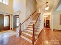 Grand foyer features hardwood floors, elegant staircase with wooden rails, and natural light at 200 Waterby Way, Matthews, NC 28104