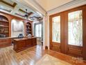 Home office boasting custom built-ins, hardwood floors, coffered ceiling, and elegant double door entry at 200 Waterby Way, Matthews, NC 28104