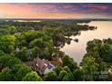 Aerial view of a beautiful waterfront home surrounded by lush trees at sunset on a beautiful lake at 2288 Brawley School Rd, Mooresville, NC 28117