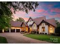 Charming stone and stucco home featuring a three-car garage, brick driveway, and beautiful landscaping at sunset at 2288 Brawley School Rd, Mooresville, NC 28117