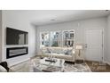 Bright living room with fireplace, modern furnishings, and a view of the neighborhood through expansive windows at 2918 Sloan Dr, Charlotte, NC 28208