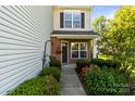 Inviting entryway of this two-story townhome with brick accents, lush greenery, and a cozy, welcoming porch at 3129 Summerfield Ridge Ln, Matthews, NC 28105