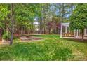 Expansive backyard with a pergola, raised garden beds, and a lush green lawn at 3617 Ruth St, Indian Trail, NC 28079