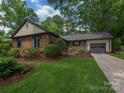 Charming brick home featuring a well-manicured lawn and mature landscaping at 6001 Charing Pl, Charlotte, NC 28211