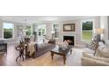 Open-concept living room boasts a fireplace, hardwood floors, and expansive windows overlooking the yard at 7105 Butternut Oak Ter, Huntersville, NC 28078