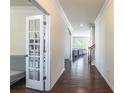 Hallway with beautiful hardwood floors leading to the living room and a glass door enclosed office at 7711 Kelburn Ln, Charlotte, NC 28273