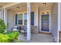 Inviting covered front porch with seating, columns, and decorative door with wreath at 8853 Brakeman Dr, Waxhaw, NC 28173