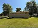 Exterior rear view of the home with a large yard, mature trees, and blue sky at 910 Absher Rd, Statesville, NC 28625