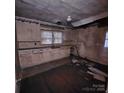 Interior shot of a kitchen with worn cabinets, damaged walls, and a deteriorated ceiling at 1015 Frederick St, Shelby, NC 28150