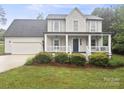 Inviting two-story home featuring a charming covered front porch, attached garage, and verdant landscaping at 10749 Kingsview Dr, Davidson, NC 28036