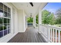 Relaxing front porch features white railings, ceiling fans, stained wood flooring and outdoor furniture at 10749 Kingsview Dr, Davidson, NC 28036