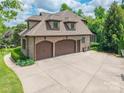 Three-car garage with a large concrete driveway, set against a backdrop of mature trees and greenery at 1260 Rittenhouse Ln, Rock Hill, SC 29732