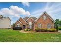 Charming brick home featuring manicured lawn and lush landscaping at 129 Daniel Efird Dr, Mount Holly, NC 28120