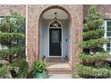 Close-up of the front door with decorative glass, brick archway, and manicured landscaping at 15247 Prescott Hill Ave, Charlotte, NC 28277
