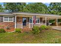 Charming brick home with a cozy covered porch and an American flag, surrounded by lush greenery at 157 E Meadowview Dr, Statesville, NC 28625