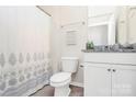 Well-lit full bathroom with granite countertop, white cabinets, and shower with patterned curtain at 174 Hanks Bluff Dr, Mooresville, NC 28117